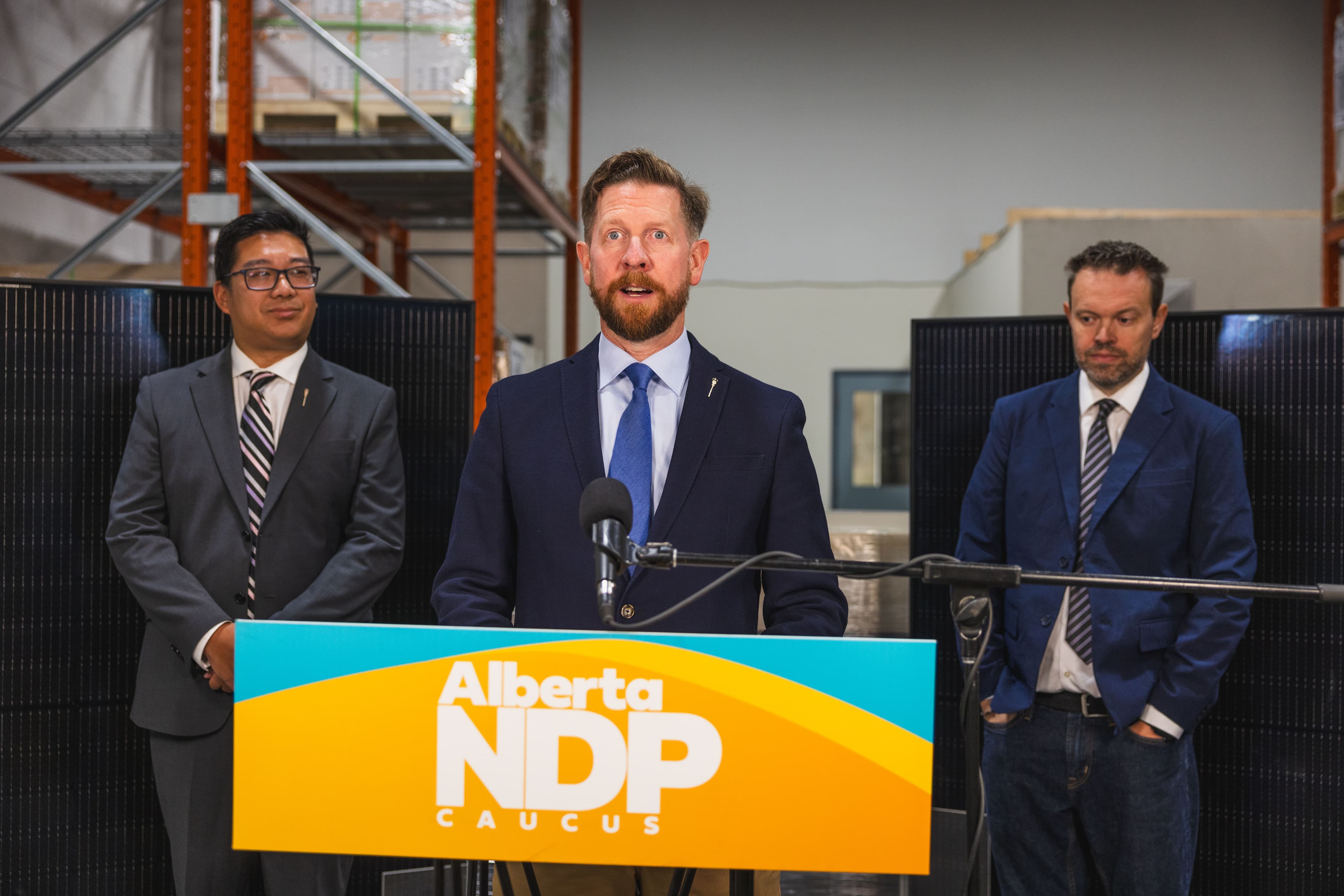 MLA Kyle Kasawski at a press conference with solar panels in the background.
