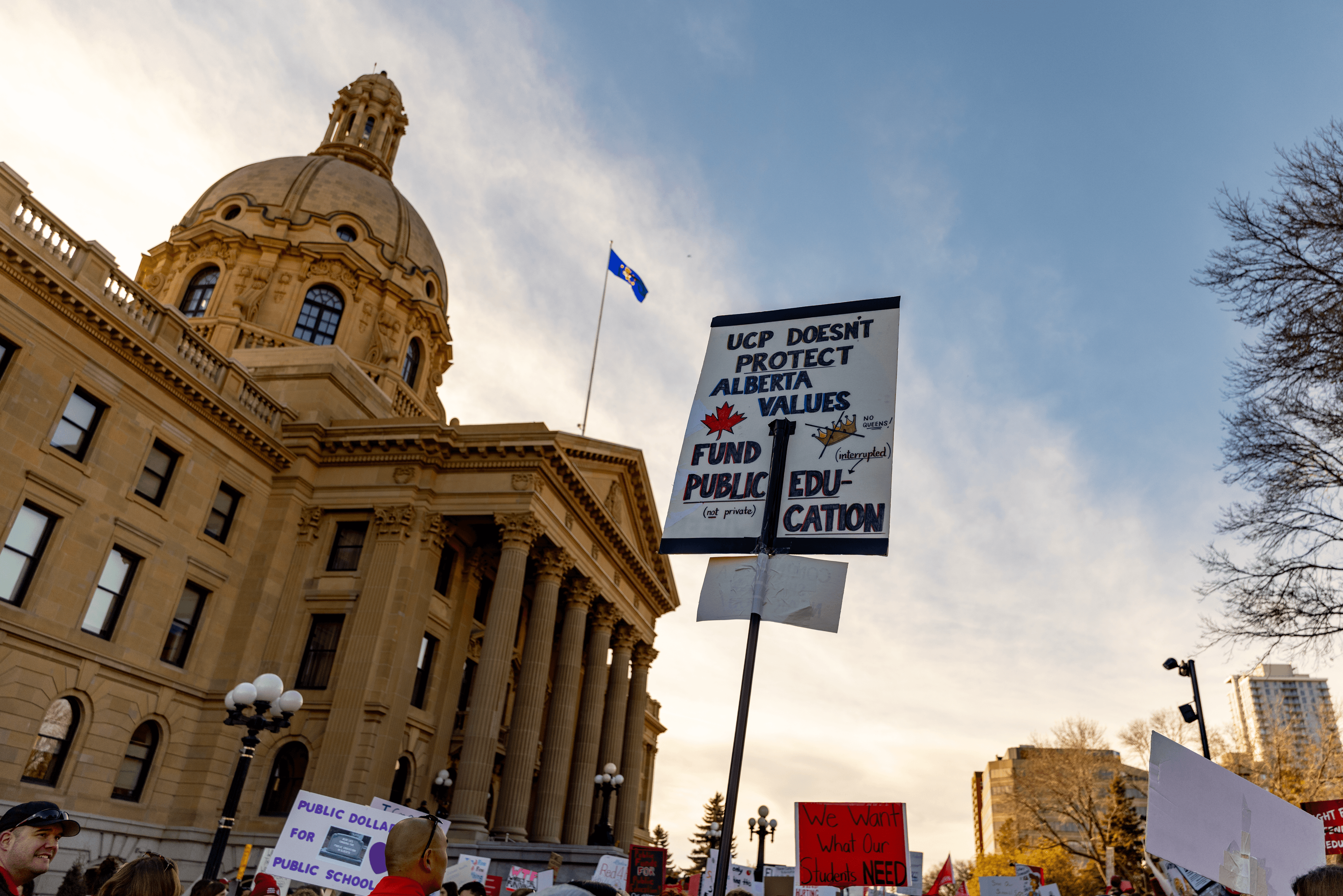 Pro-public education signs held high, shadowed by the Alberta Legislature.
